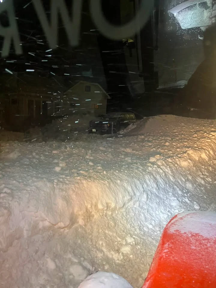 View from the tractor cab during nighttime residential snow clearing