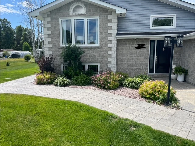 Front garden along a stone-faced home and curved walkway — before, pair 16 of 36