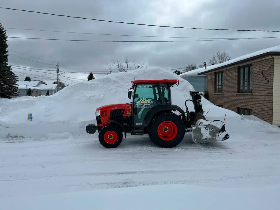 Picture Perfect tractor with a rear snowblower beside a high residential snowbank