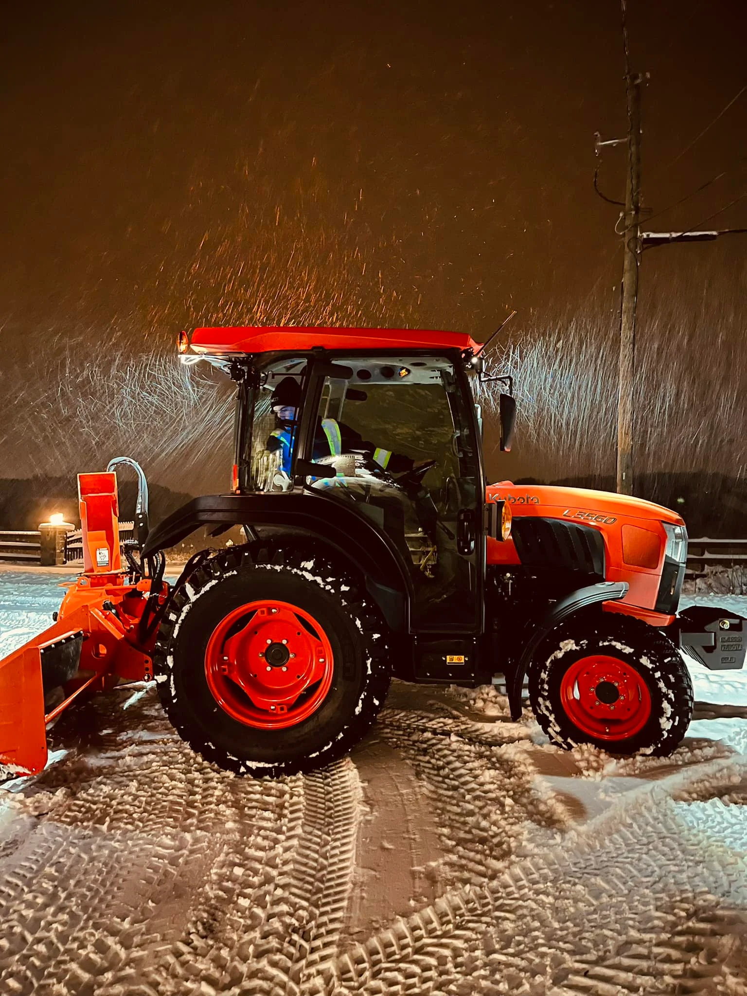 Orange snow-clearing tractor at night